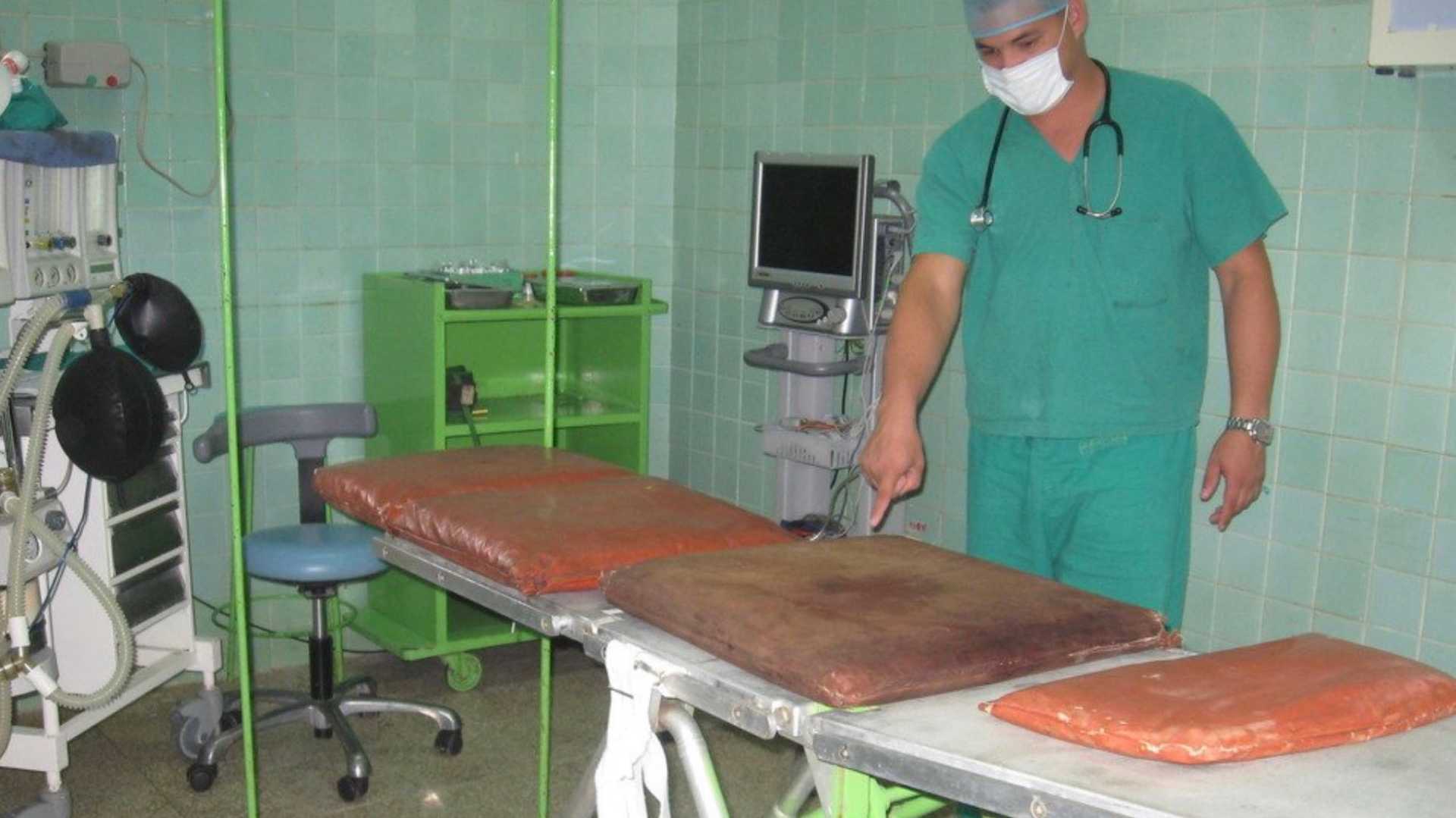 a doctor showing a disgusting mattress in a hospital in Cuba